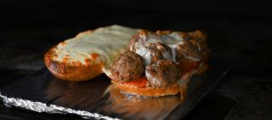 A delicious meatball sandwich on pizza bread in the oven